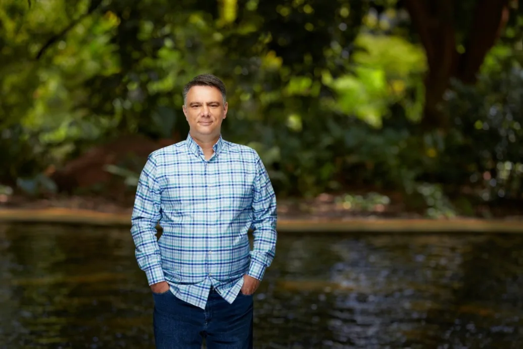 Milos Pavlovic standing beside a river, with dense green vegetation behind.